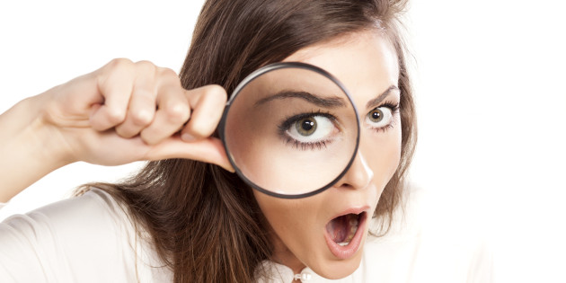 shocked young woman looking through a magnifying glass
