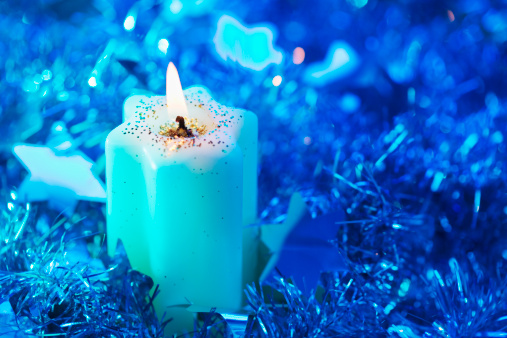 Lighted candle arrangement surrounded by Christmas decorations